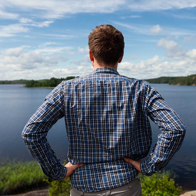 man standing on the shore of a lake looking outward for a dock