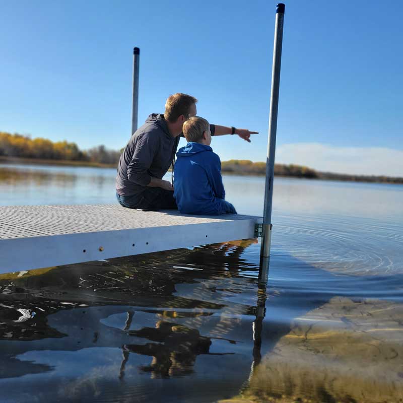 Father and Son sitting on  the end of a Patriot Dock.